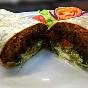 Un burrito partido a la mitad: arroz, frijoles, carne, guacamole y crema
